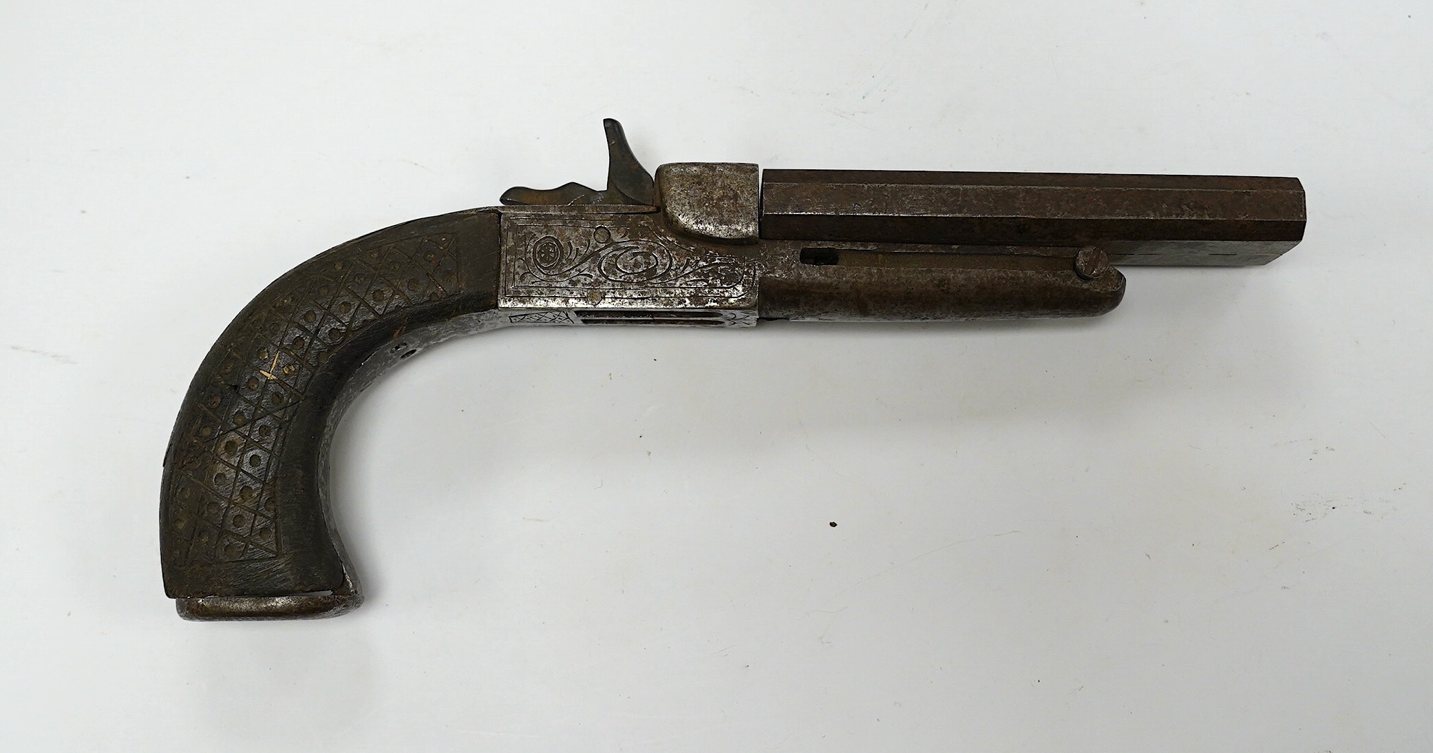 An early 19th century double-barrelled breach loading percussion pistol in relic condition, steel barrels, engraved frame, and walnut two piece grip, one piece missing, one piece detached, folding triggers, both missing